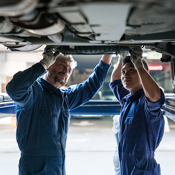 Mature car mechanic and apprentice at work