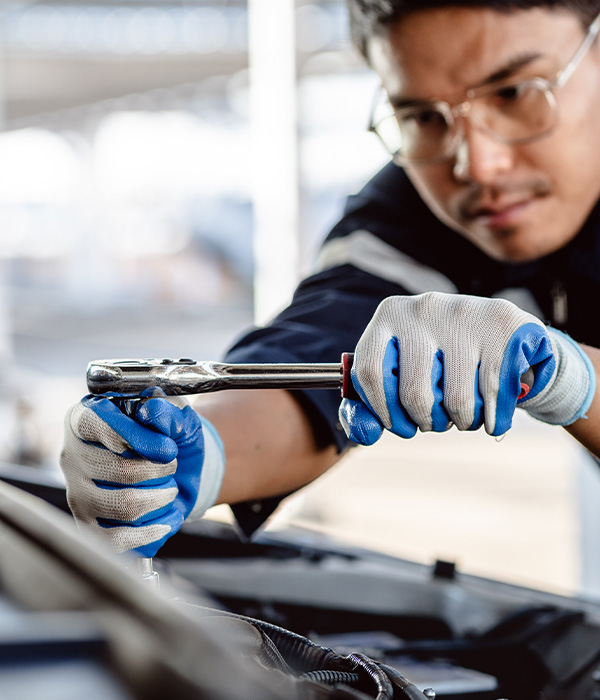 Auto mechanic repairman using a socket wrench working engine repair in the garage